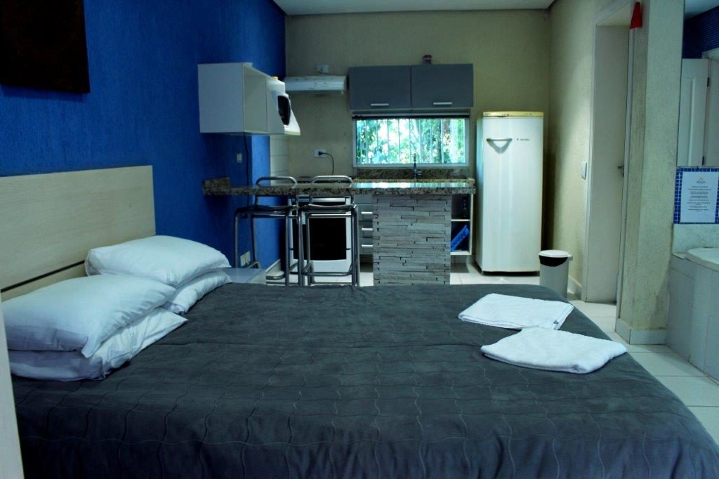 Cama e Cozinha da suíte Cayo Largo na Pousada Refúgio do Éden no Guarujá, litoral de São Paulo (Divulgação / La Viagem)